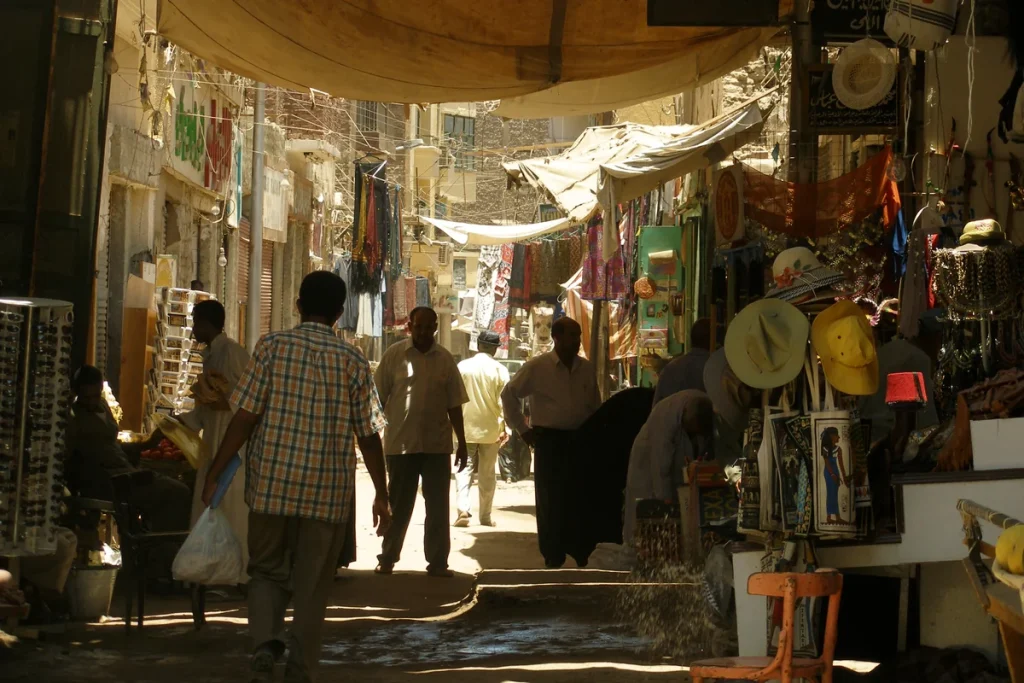 People walking through a shaded shopping street in Aswan